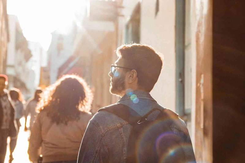 Man wandert durch die Stadt w&auml;hrend Sonne auf ihn scheint